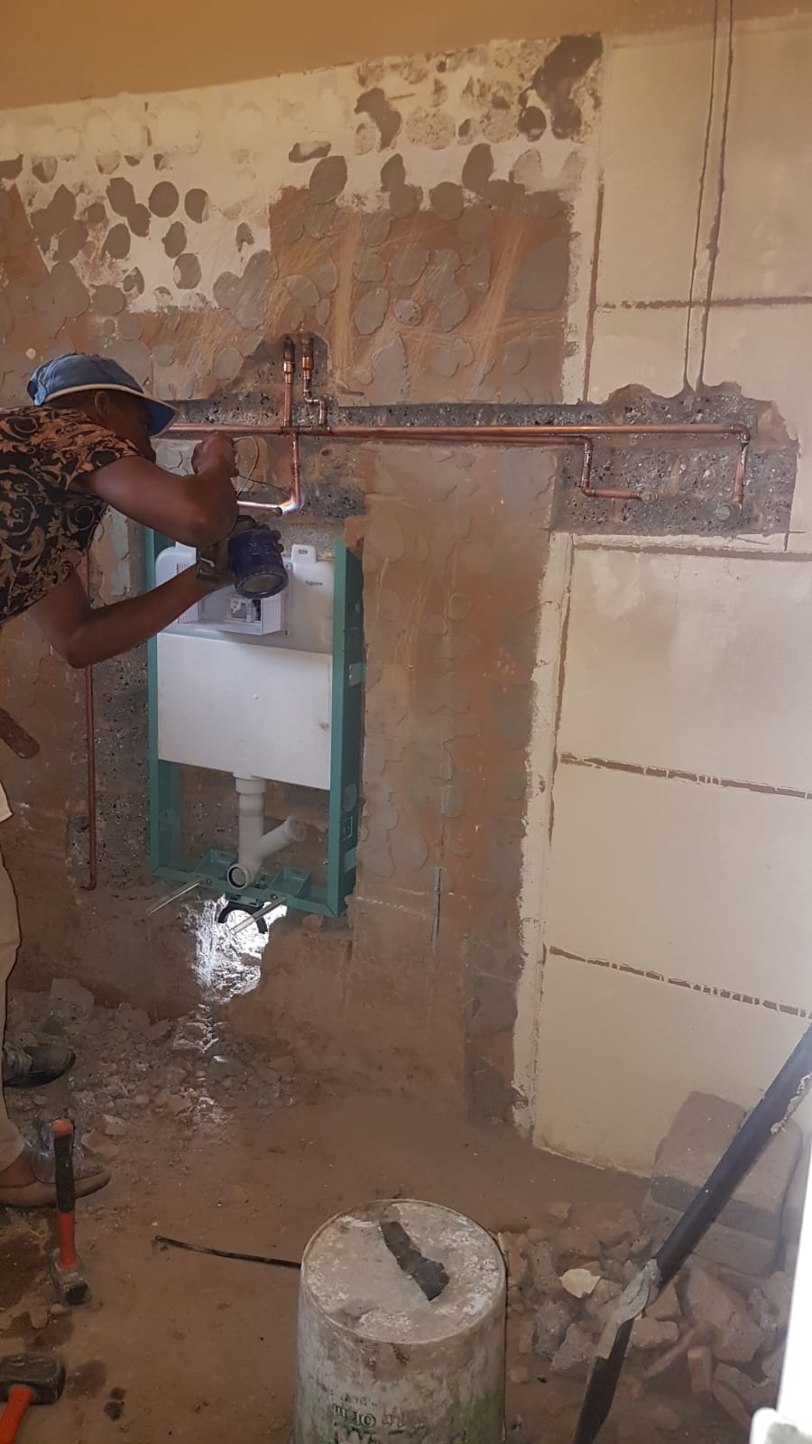 Bathroom renovation in progress showing exposed plumbing and stripped walls
