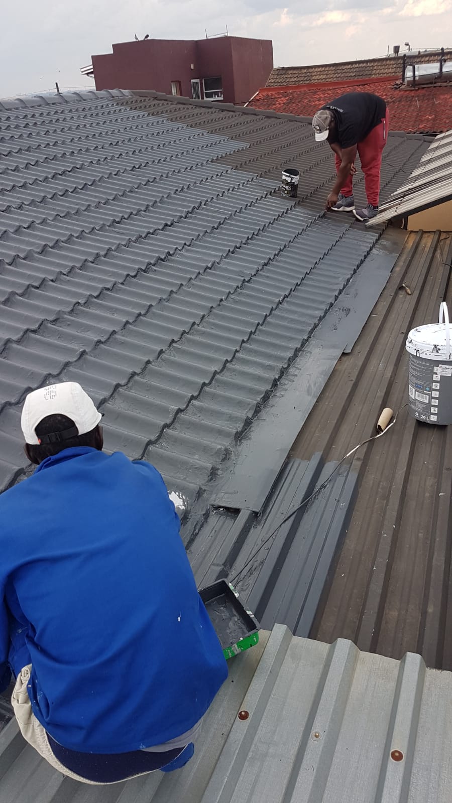 Workers applying waterproofing along a roof